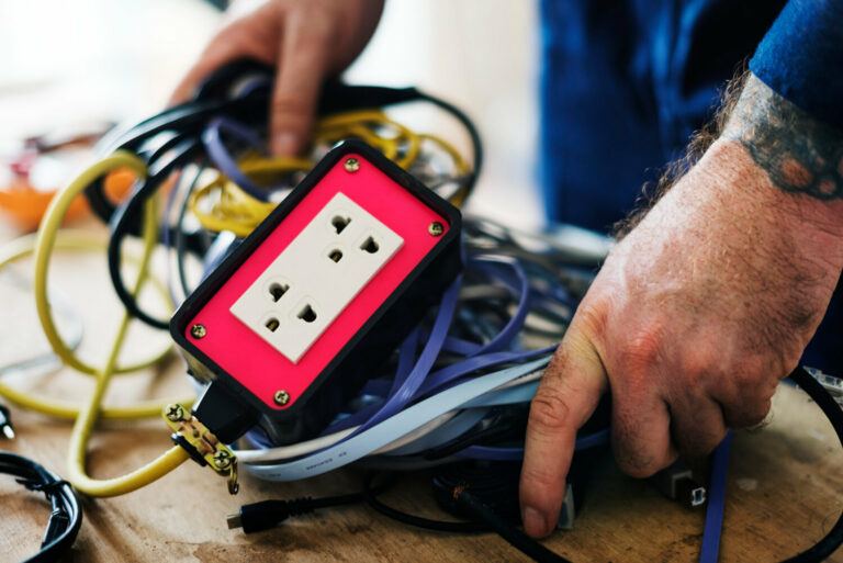 Électricien en atelier, effectuant une installation ou réparation électrique.