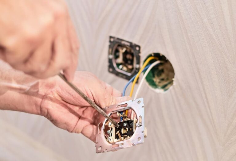 Image des mains d'un électricien installant une prise électrique dans une nouvelle maison.